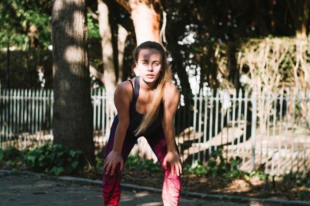 Sporty woman leaning on knees during training