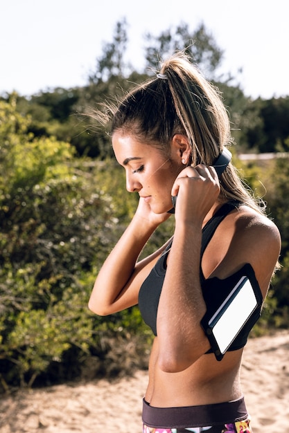 Sporty woman putting on headphones