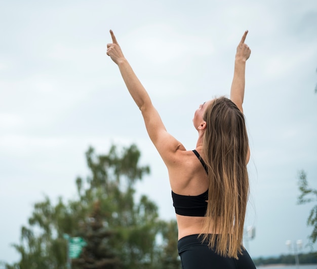 Sporty woman raising her hands up