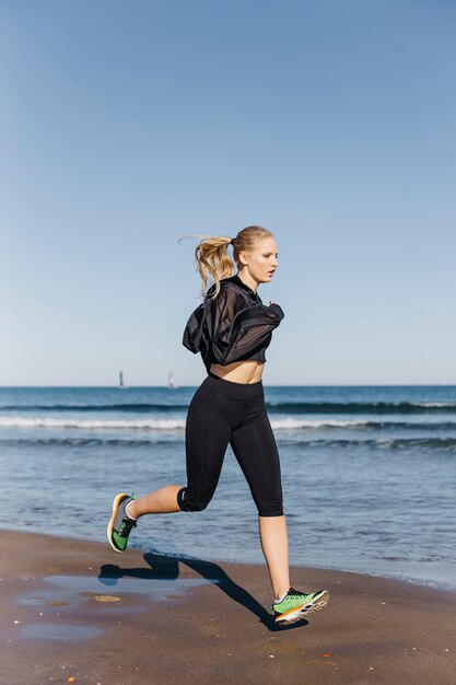 Sporty woman running at shoreline