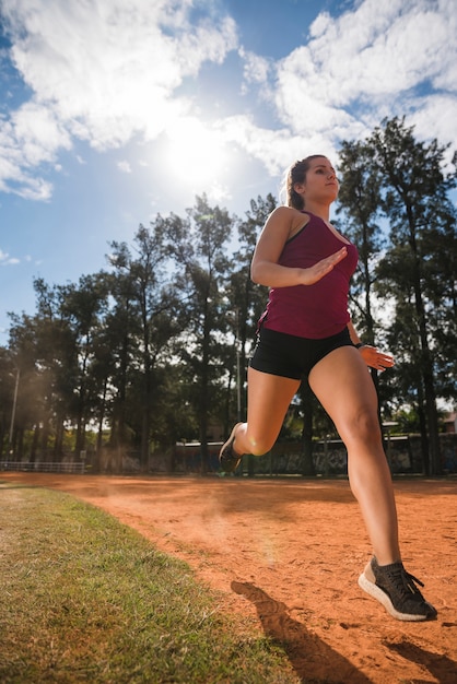 Donna sportiva che corre sulla pista dello stadio