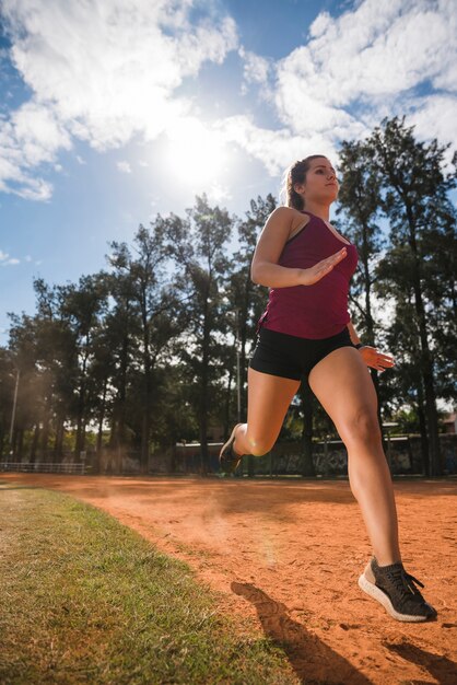 スタジアムのトラックで走っているスポーティな女性