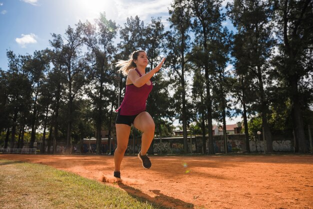 スタジアムのトラックで走っているスポーティな女性