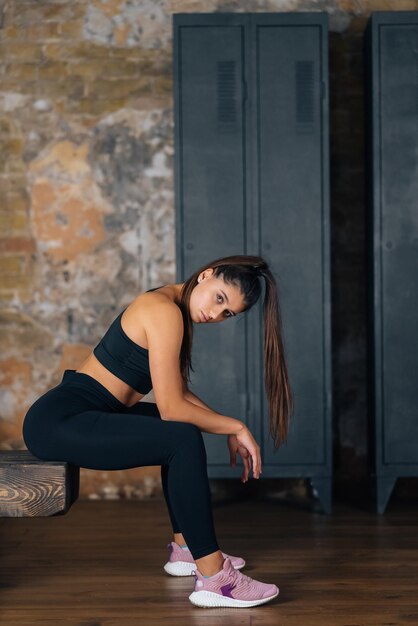 Sporty woman in sportswear resting on bench at fitness