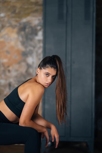 Sporty woman in sportswear resting on bench at fitness