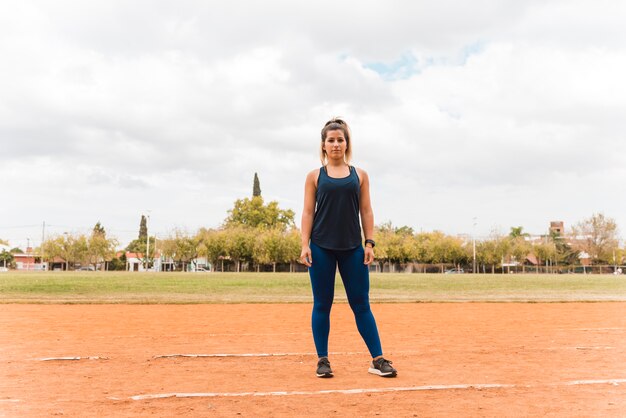 スタジアムのトラックの上に立っているスポーティな女性