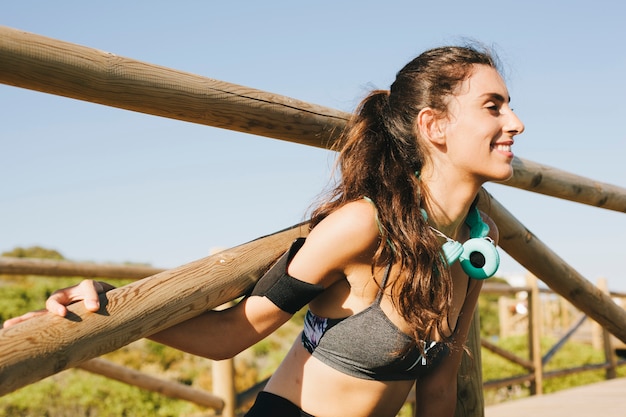 Sporty woman stretching arms at fence close up view