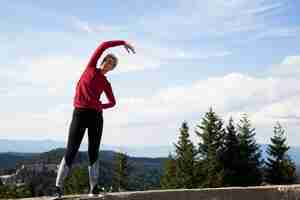 Foto gratuita donna sportiva che si estende in natura