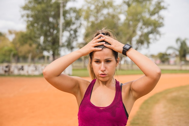 スポーティな女性のスタジアムのトラックでストレッチ