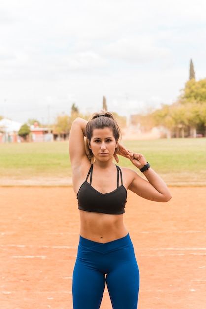 Sporty woman stretching on stadium track