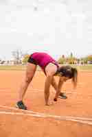 Foto gratuita donna sportiva che si estende sulla pista dello stadio