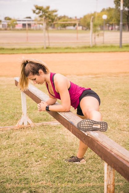 スポーティな女性のスタジアムのトラックでストレッチ