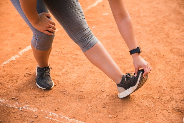 スポーティな女性のスタジアムのトラックでストレッチ