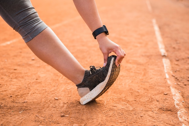 スポーティな女性のスタジアムのトラックでストレッチ