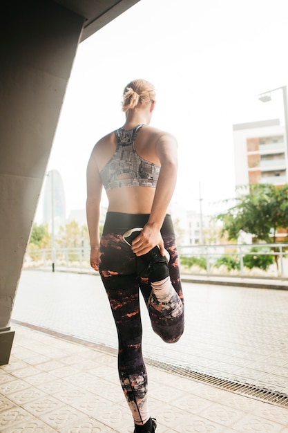 Sporty woman stretching in urban environment