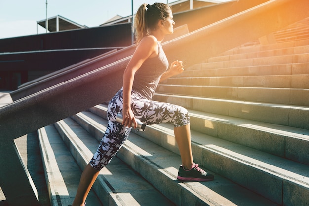 Foto gratuita donna sportiva che si estende in ambiente urbano