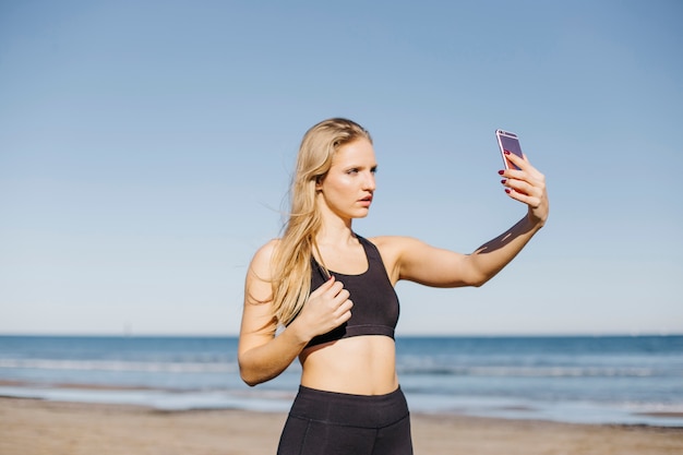 Donna sportiva che prende selfie in spiaggia