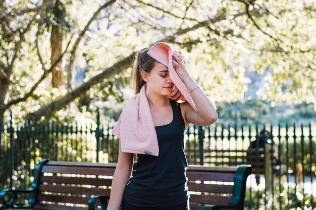 Sporty woman wiping face with towel