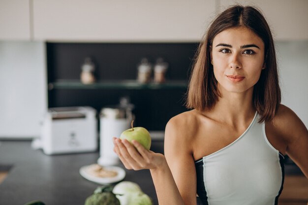 Sporty woman with apple at the kitchen