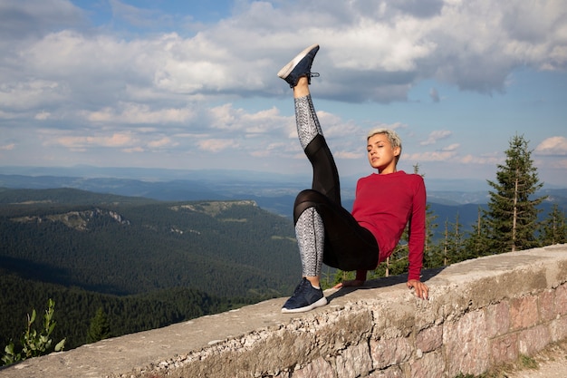 Sporty woman with short hair stretching in nature