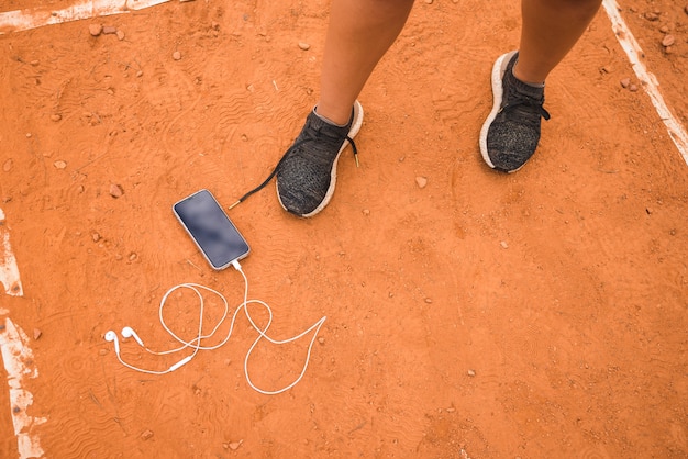 Foto gratuita donna sportiva con smartphone sulla pista dello stadio