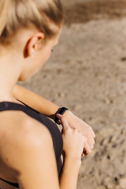 Donna sportiva con smartwatch in spiaggia