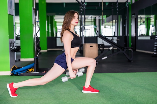 Free photo sporty woman with strong fit body is doing different exercises in modern sportclub with mirrors