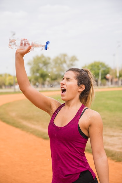 スタジアムトラック上の水のボトルを持つスポーティな女性