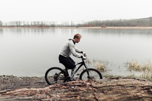 Sporty young man riding bicycle near the lake