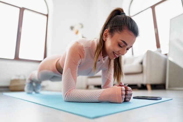 Спортивная молодая женщина делает упражнения на доске в помещении дома