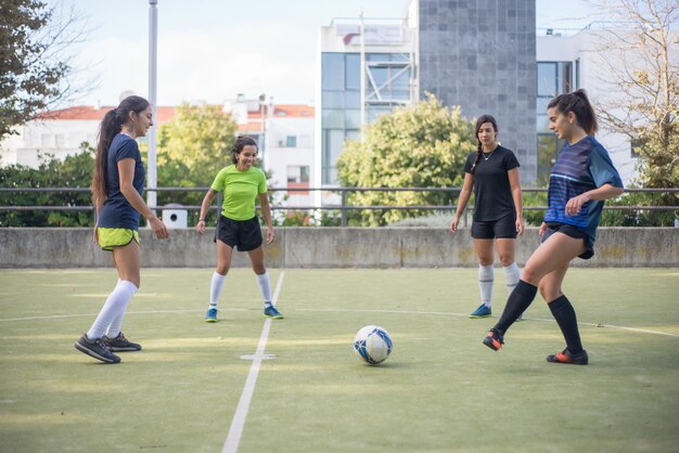 축구장에서 훈련하는 스포티한 젊은 여성. 화려한 유니폼을 입은 스포츠 여성들은 원에 서서 공을 차고 워밍업을 합니다. 스포츠, 레저, 활동적인 라이프 스타일 개념