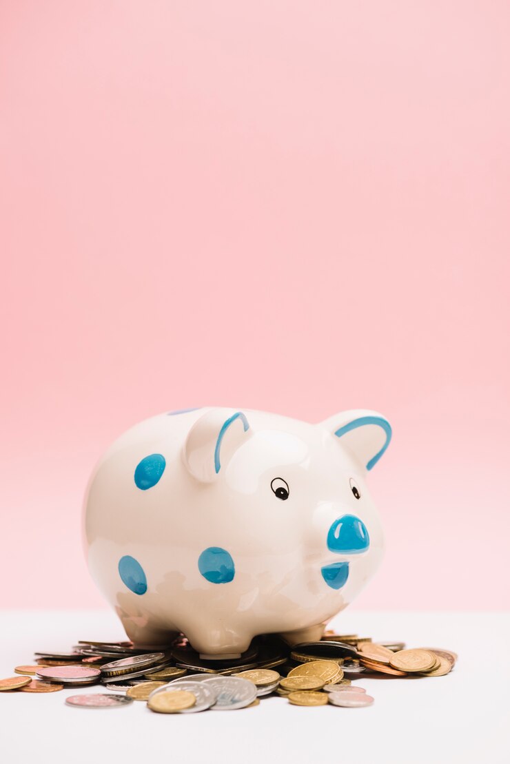 Free Photo spotted ceramic piggybank over coins against pink background