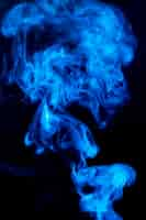 Free photo spread dense blue swirl smoke on black background