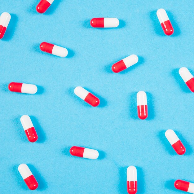 Spread red and white capsules on blue background