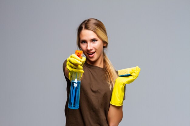 ゴム手袋とクリーニング製品で笑顔で春の大掃除の準備ができている春の大掃除の女性。白で隔離のかなり笑顔の若い女性。