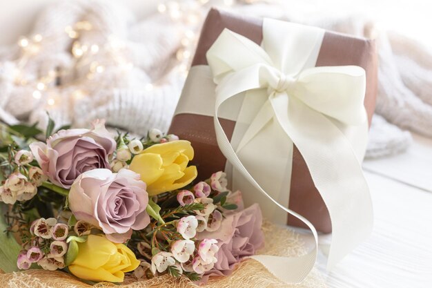 Spring composition with flowers and a gift box on a blurred background