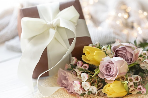 Free photo spring composition with flowers and a gift box on a blurred background