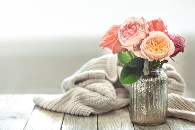 Spring composition with flowers in a glass vase on a knitted element on a wooden table.