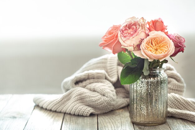 Spring composition with flowers in a glass vase on a knitted element on a wooden table.