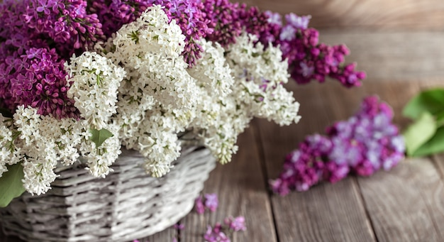 Spring composition with lilac flowers in a wicker basket. Mothers and womens day. Space for text. Horizontal orientation. Gift baskets and flower deliveries