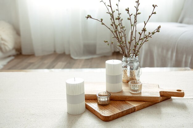 Spring composition with young twigs in a vase with candles in the interior of the room.