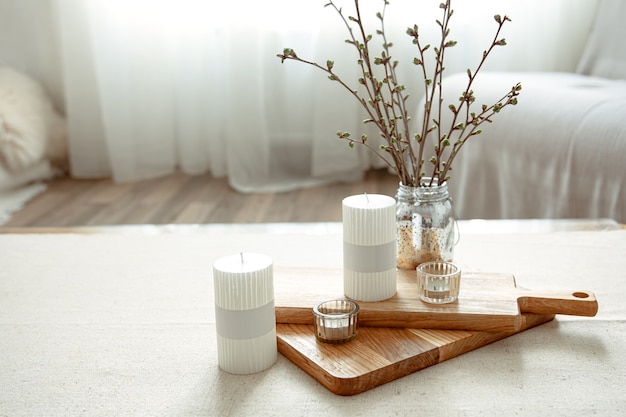 Spring composition with young twigs in a vase with candles in the interior of the room.