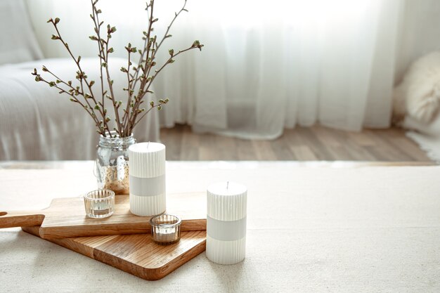 Spring composition with young twigs in a vase with candles in the interior of the room.