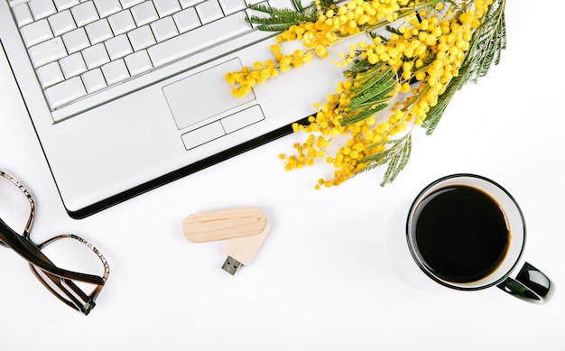 Set festoso di primavera con fiori e un computer portatile su uno sfondo bianco