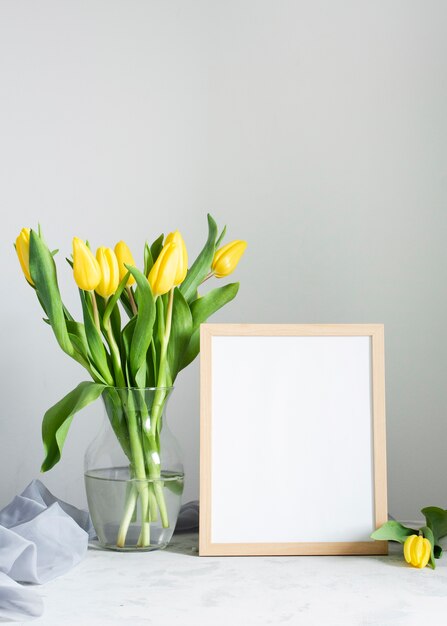 Spring flowers in vase with frame beside