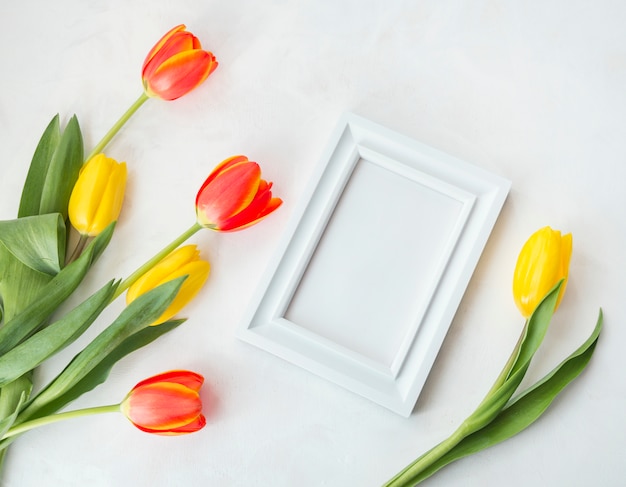 Spring flowers with empty frame placed on desk