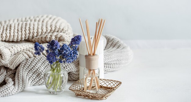 Spring home composition with flowers, aroma sticks and knitted element copy space.