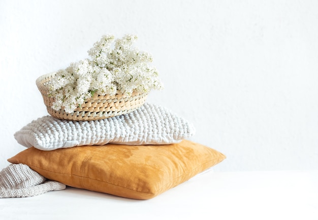 Spring lilac blooms in the interior of the room with decorative pillows. On light background.