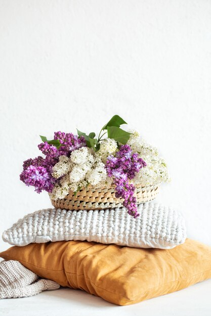 Spring lilac blooms in the interior of the room with decorative pillows