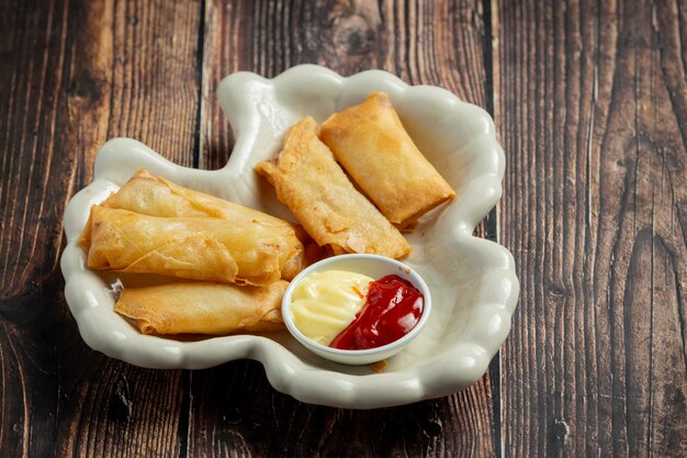 Spring rolls with cheese on dark wood background